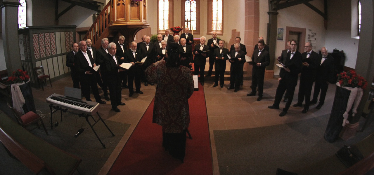 Spectacle de chorale dans une église où l'on voit les chanteurs habillés en tuxedo regroupés ensemble.