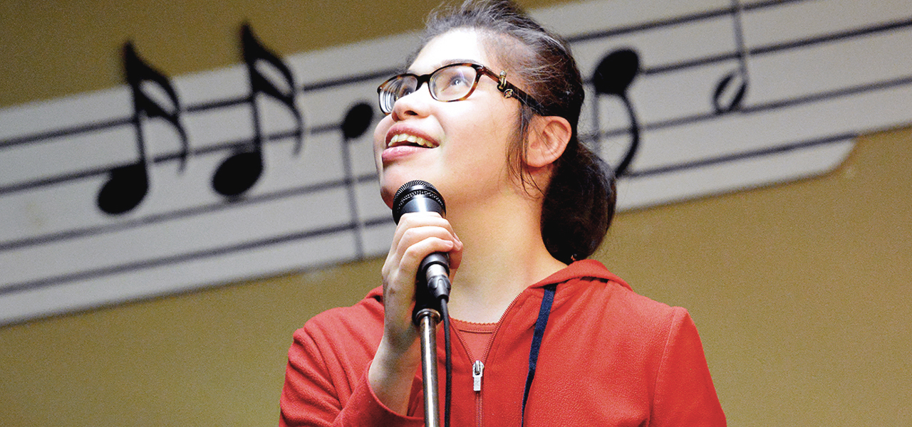 Jeune adolescente ayant une déficience visuelle en train de chanter lors du spectacle organisé par Musique O Max.