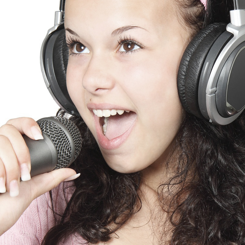 Gros plan d'une jeune fille adulte qui portent des écouteurs et elle est devant un micro.