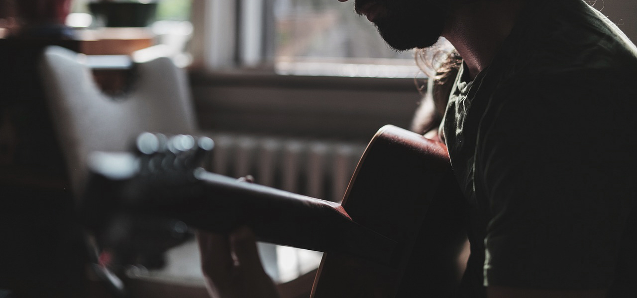 Un homme jouant de la guitare sur une scène peu illuminée.