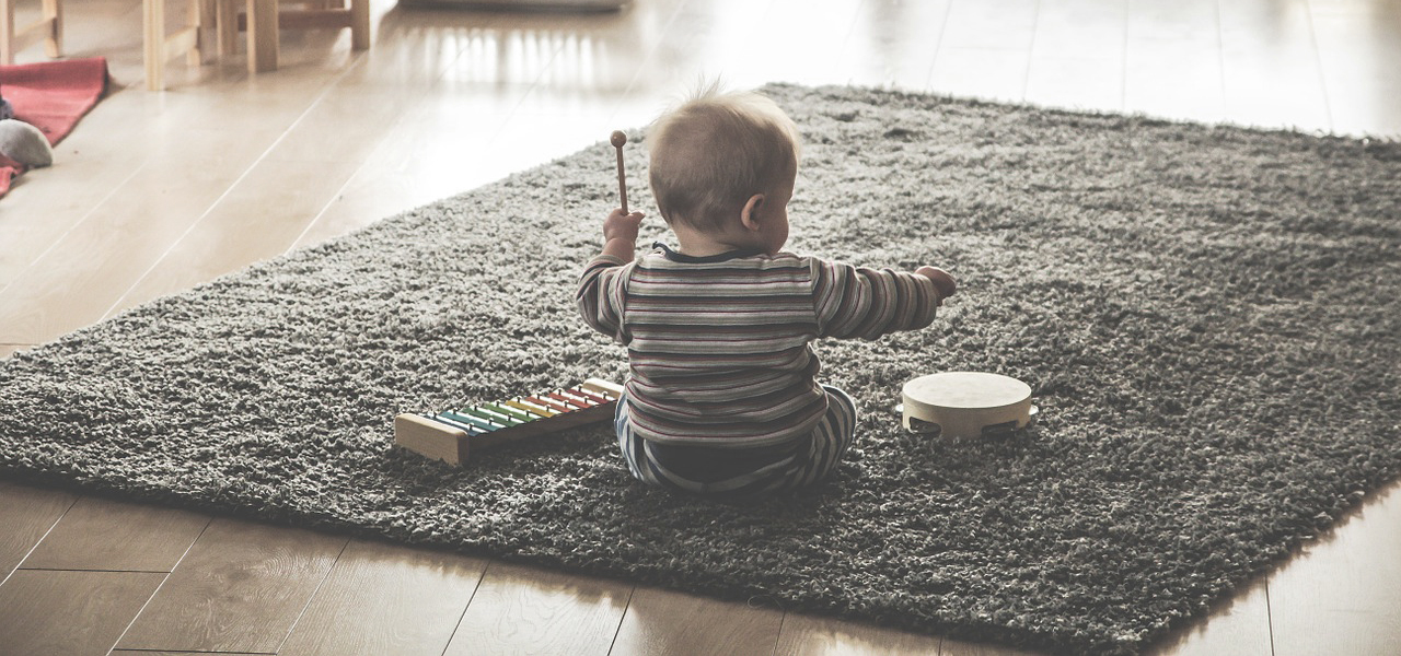 Petit enfant de 3-4 ans avec un petit tambour à sa droite et un xylophone à sa gauche.