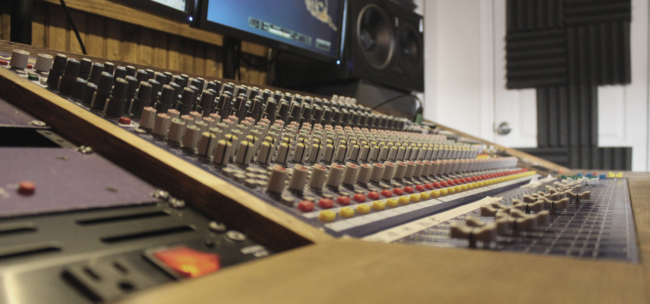 Gros plan sur une console de studio d'enregistrement contenant de nombreux boutons.