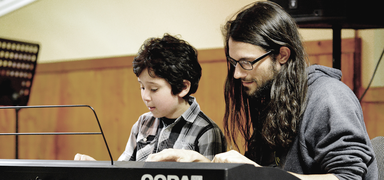 Jeune fille accompagnée par son professeur en train de jouer du piano lors du spectacle organisé par Musique O Max.